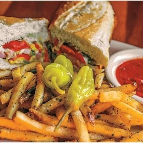 A Li'l Nick's Pizza sub sandwich, seasoned fries, two green peppers, and a side of red sauce.